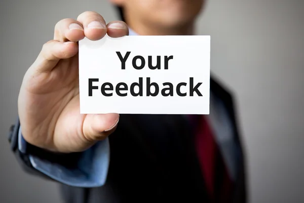 Affärsman som presenterar "Din feedback" ord på vitt kort — Stockfoto