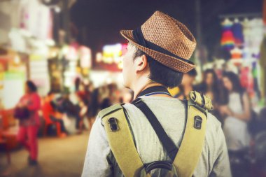 Asya'da bir ünlü sokak gece pazarda yürüyen genç erkek backpacker