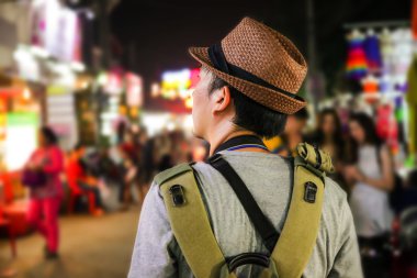 Asya'da bir ünlü sokak gece pazarda yürüyen genç erkek backpacker