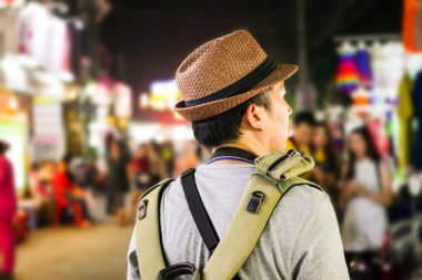 Asya'da bir ünlü sokak gece pazarda yürüyen genç erkek backpacker