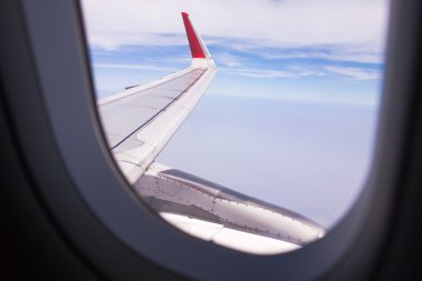 Bir uçağın penceresinden bulutlar ve mavi gökyüzü looing