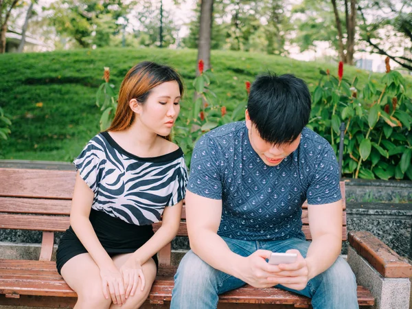 Jealous girlfriend peeking and spying her boyfriend mobile phone while he is reading a message — Stock Photo, Image