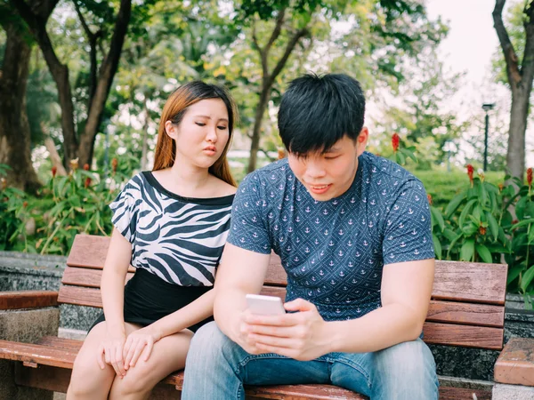 Jealous girlfriend peeking and spying her boyfriend mobile phone while he is reading a message — Stock Photo, Image