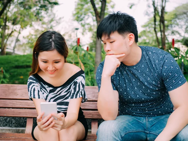 Jealous boyfriend peeking and spying his girlfriend mobile phone while she is reading a message — Stock Photo, Image