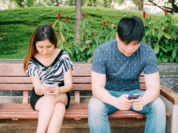 Young couple playing with smartphones and ignoring each other — Stock Photo, Image