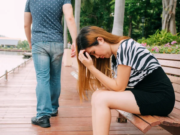 Breakup of a couple with sad girlfriend and boyfriend walking away with city in the background — Stock Photo, Image