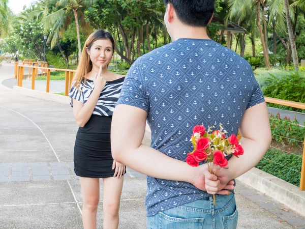 Jovem escondendo rosas de suas costas e dá-los a sua namorada — Fotografia de Stock