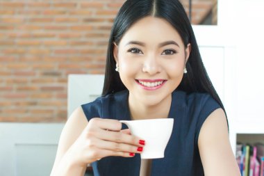 Asyalı kadın yüzündeki gülümseme ile kahve içme