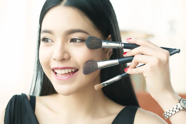 Asian woman holding brushes - beauty makeup concept