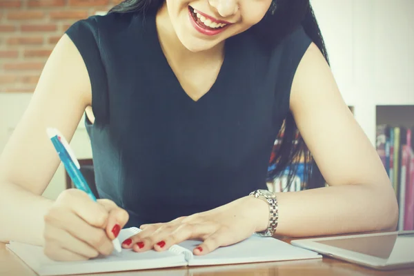 Красивая женщина улыбается и пишет блокнот на столе — стоковое фото