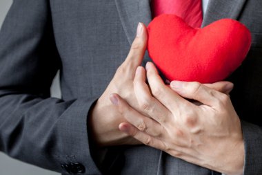 Onun göğsünde onun takım elbise - crm, hizmet zihin iş kavramı kırmızı kalp tutunarak şefkat gösteren işadamı