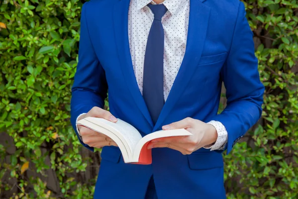 Jonge zakenman leesboek op groene natuur achtergrond — Stockfoto