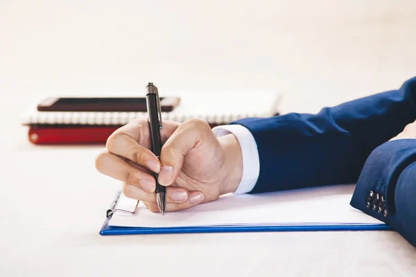 Closeup of Businessman writing on paper on notepad — Stock Photo, Image