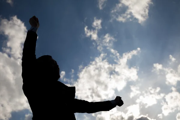 Silhueta de homem de negócios feliz levantando braços contra o céu azul — Fotografia de Stock