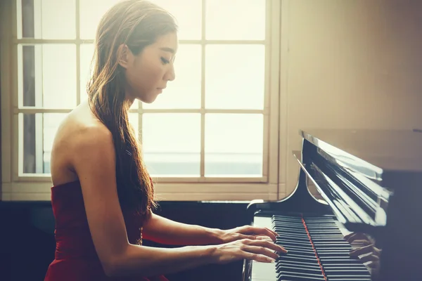 Asiatico donna giocare pianoforte in finestra sfondo con luce coming — Foto Stock