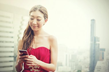 Mutlu gülümseyen Asyalı kadın kentsel city scape sahnede binanın çatı telefon kullanma