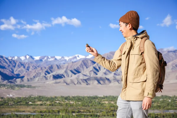 インド、ラダック、リーのヒマラヤ山の景色の背景でコンパスを見ているアジアの若い旅行者 — ストック写真