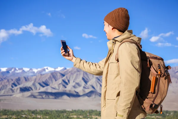 若いアジアのハイカーは、インドのラダック州レーの山頂にあるスマートフォンを使って — ストック写真
