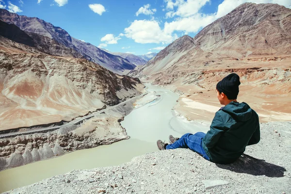 Young happy man sitting on the cliff on the trip in Indus River in Leh, Ladakh, India — Stock Photo, Image