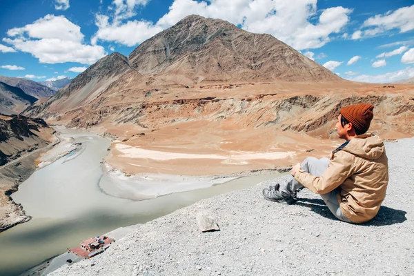 Young happy man sitting on the cliff on the trip in Indus River in Leh, Ladakh, India — Stock Photo, Image