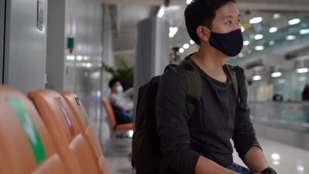 20s jovem adulto asiático homem turista mochileiro segurando bilhete de avião usando uma máscara facial com um bilhete de voo no aeroporto. Distanciamento social conselhos de segurança de viagem durante Covid-19 — Vídeo de Stock