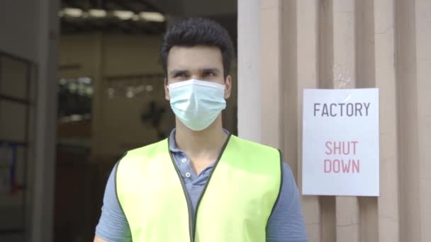Jovem indiano fábrica armazém trabalhador vestindo uma máscara protetora rosto e capacete de segurança com sinal de aviso de desligamento de fábrica — Vídeo de Stock