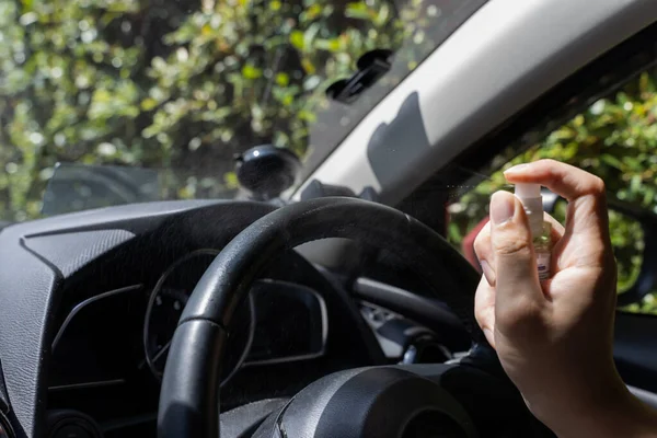 Menschliche Hand mit Alkoholspray, um Lenkrad im Auto zu desinfizieren. Sprühen verhindert Infektion mit Coronavirus Covid-19 — Stockfoto