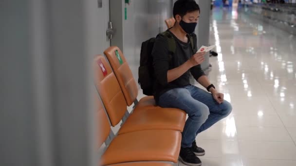 20 giovane adulto asiatico turista zaino in spalla in possesso di biglietto aereo con indosso una maschera viso con un biglietto aereo in aeroporto. Consigli sulla sicurezza sociale durante Covid-19 — Video Stock