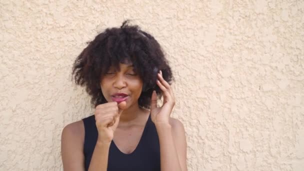 Afro saçlı genç Afrikalı Amerikalı kadın sokakta kulaklıkla şarkı söylüyor. Kadın zenci şarkıcı mutlulukla müzik dinliyor.. — Stok video