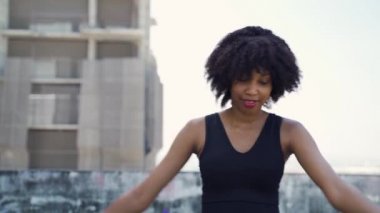 Genç Afro-Amerikan sağlıklı kadın şehir parkında fitness eğitiminden önce sabah esnemesi yapıyor. Spor yapan bayan sporcu kollarını dışarıda ısıtıyor.