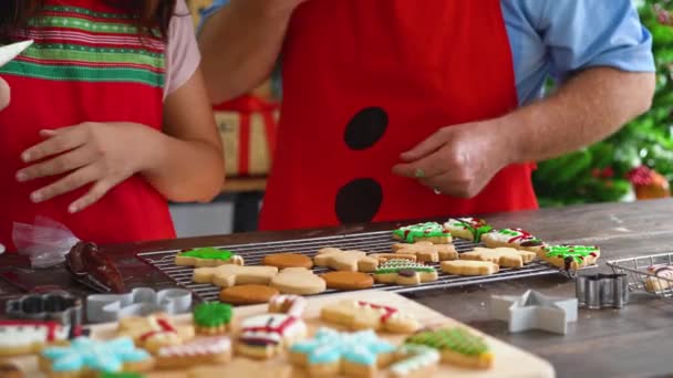 Senior far og teenager datter gør cookies sammen med juletræ i baggrunden. Lykkelig familie fejrer i santa hat derhjemme – Stock-video