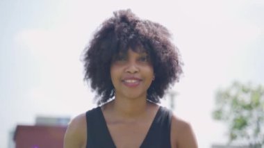 Afro saçlı genç Afrikalı Amerikalı kadın sabah açık havada koşuyor. Mutlu kadın zenci koşucunun güzel yüzü güneş ışığıyla egzersiz yapıyor.