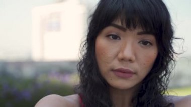 Genç Asyalı sağlıklı bir kadın şehir parkında spor yapmadan önce sabah esnemesi yapıyor. Spor yapan bayan sporcu kollarını dışarıda ısıtıyor.