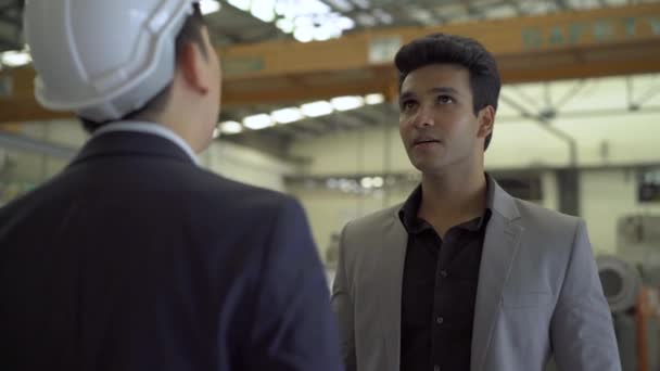 30s joven empresario indio en traje formal y sombrero duro que tiene negocios hablando en el fondo de la fábrica. Asociación empresarial y trabajo en equipo concepto de éxito — Vídeos de Stock