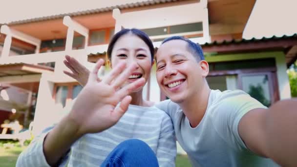 Retrato de pareja asiática adulta joven de 30 años haciendo una videollamada en un teléfono inteligente y mostrando su nueva casa. Marido y esposa como nuevos propietarios de viviendas. Logro inmobiliario para nuevos amantes casados — Vídeos de Stock