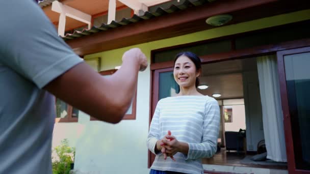 Třicátník mladý dospělý Asiat drží nový dům klíč překvapí ženu s nadšením. Manžel a manželka majitelé nemovitostí se objímají doma. Koncepce realizace investic do bydlení. — Stock video