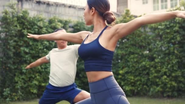 Joven pareja de fitness practicando yoga de saludo al sol posan al aire libre en el jardín de casa. Mujer asiática y hombre caucásico entrenando al aire libre en el parque — Vídeos de Stock