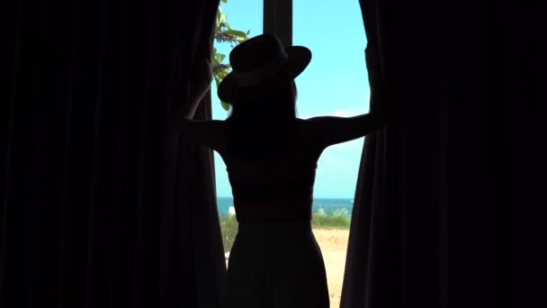 Mujer joven abriendo las cortinas y viendo a través de la ventana de la playa del mar en el complejo hotelero de lujo — Vídeo de stock