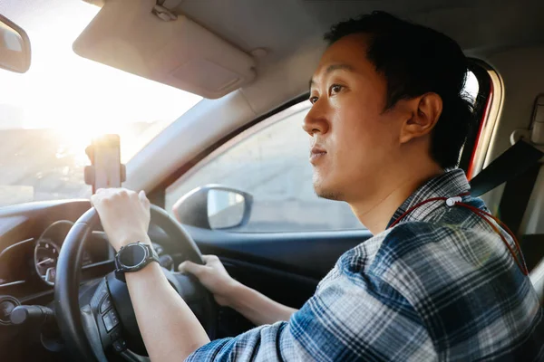 Junger asiatischer Mann blickt auf die Stadtstraße, während er in der Stadt Auto fährt — Stockfoto