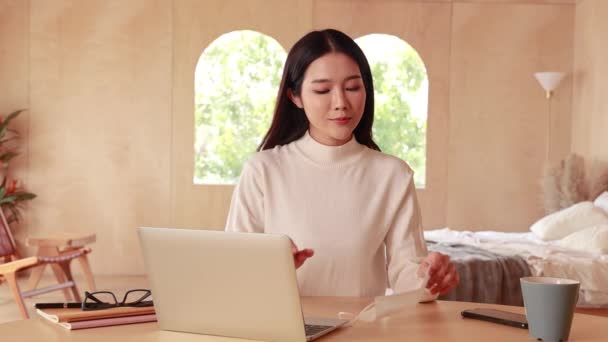 Junge Asiatinnen im Teenageralter tragen Pullover mit Computer-Laptop, der von zu Hause aus online arbeitet. Attraktives Mädchen mit Gesichtsmaske, um die Ausbreitung von Covid-19 - Coronavirus-Pandemie zu verhindern. Kopierraum. — Stockvideo