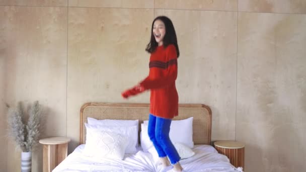 幸せなアジアの女性ジャンプオンベッド — ストック動画