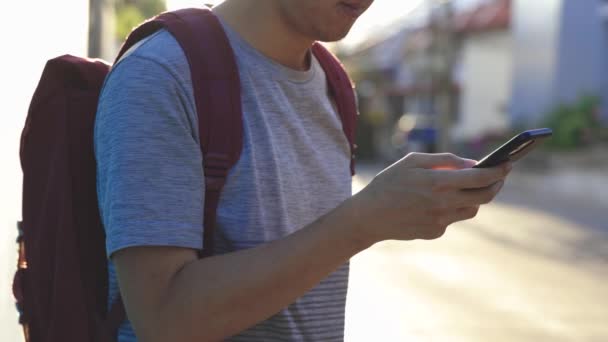 Närbild av ung man med hjälp av en mobiltelefon i stadsdelen utomhus solnedgång — Stockvideo