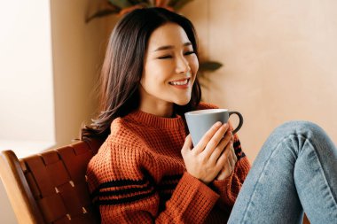 Asyalı kadın evde sıcak içkinin tadını çıkarıyor.