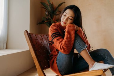 Bunalımlı üzgün kız kışın evde oturup pencereden dışarı bakıyor. Asyalı kadın akıl sağlığı konusunda dengesiz hissediyor. Depresyon kavramı, yalnızlık, endişe, keder duyguları.