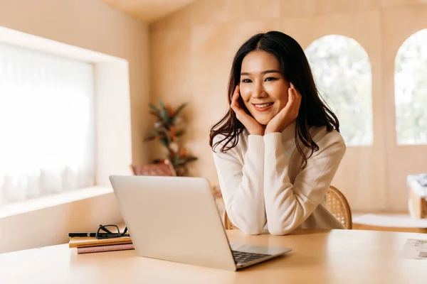 Молодая азиатка-подросток носит свитер с красивой улыбкой в гостиной. Счастливая и успешная девушка, использующая ноутбук с ноутбуком. Зимний портретный стиль жизни. Копирование пространства — стоковое фото