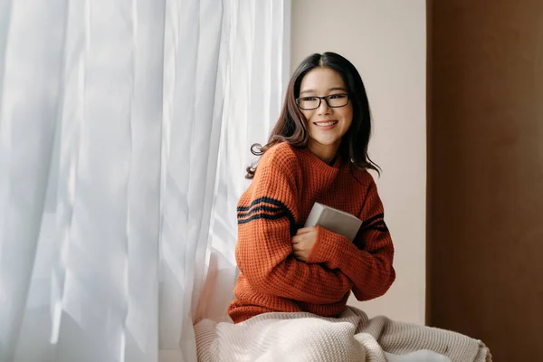 Азиатка с книгой у окна — стоковое фото