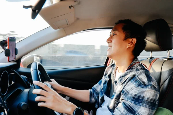 Mladý asijský muž s úsměvem a při pohledu na městské silnici při jízdě autem ve městě — Stock fotografie