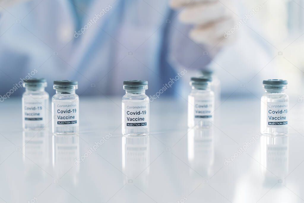 COVID-19 Coronavirus vaccine tubes with medical doctor behind
