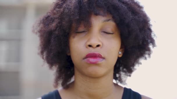 Jonge Afro-Amerikaanse vrouw in afro kapsel kijkend naar camera en glimlach op daken. Extreme gezicht close-up van vrouwelijke gelukkig en zelfverzekerde zwarte dame in natuurlijk positieve expressie — Stockvideo