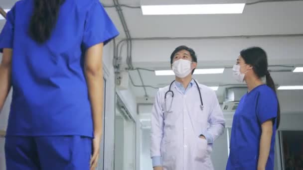 Счастливая и молодая азиатская команда врачей и медсестер в форме и халате со стетоскопом и хирургической маской дают друг другу пять очков. — стоковое видео